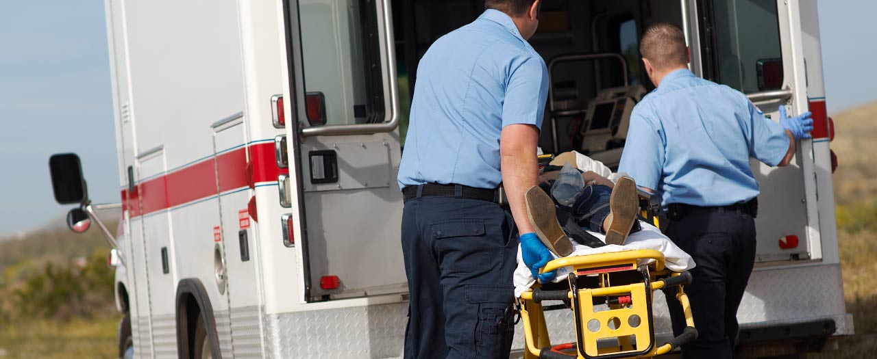 Two paramedics moving a crash victim into an ambulance