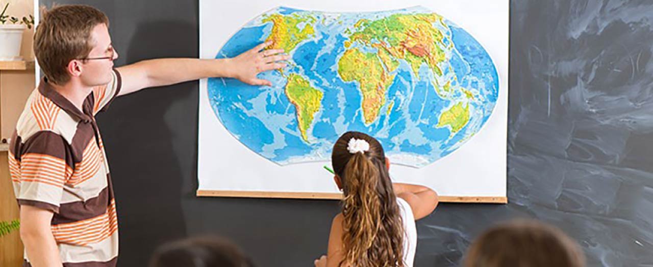 Teacher asking young student to locate a specific place on a world map