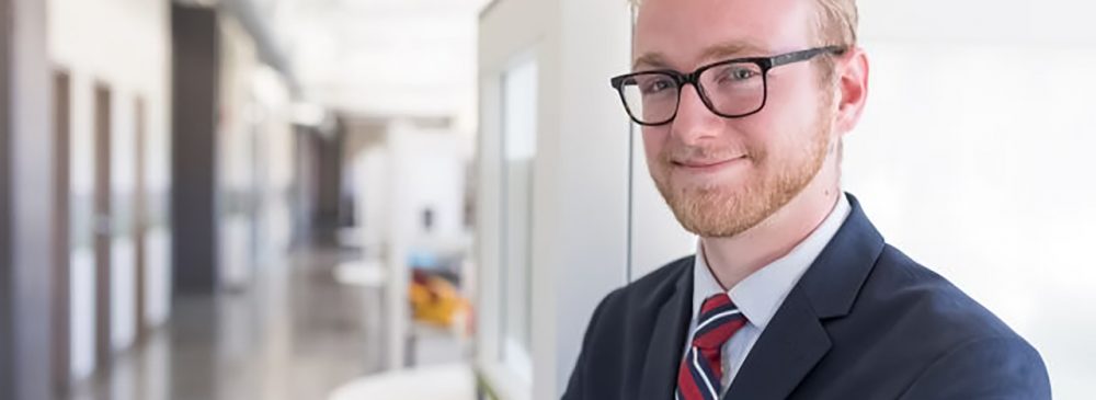 Psychology Graduate Jason Tate wearing a suit, smiling