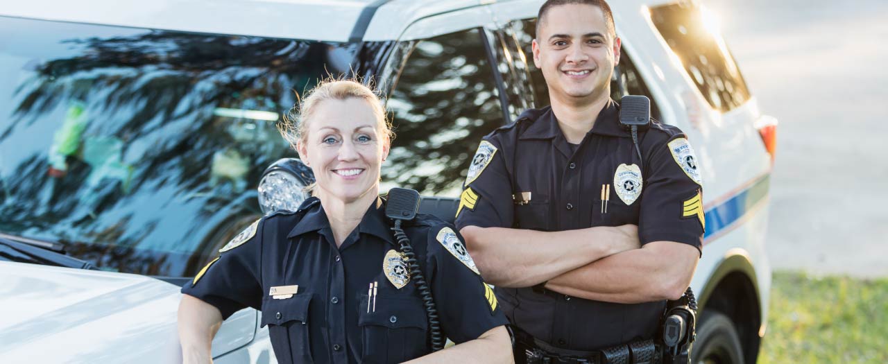 Two police officers smiling next to cruiser